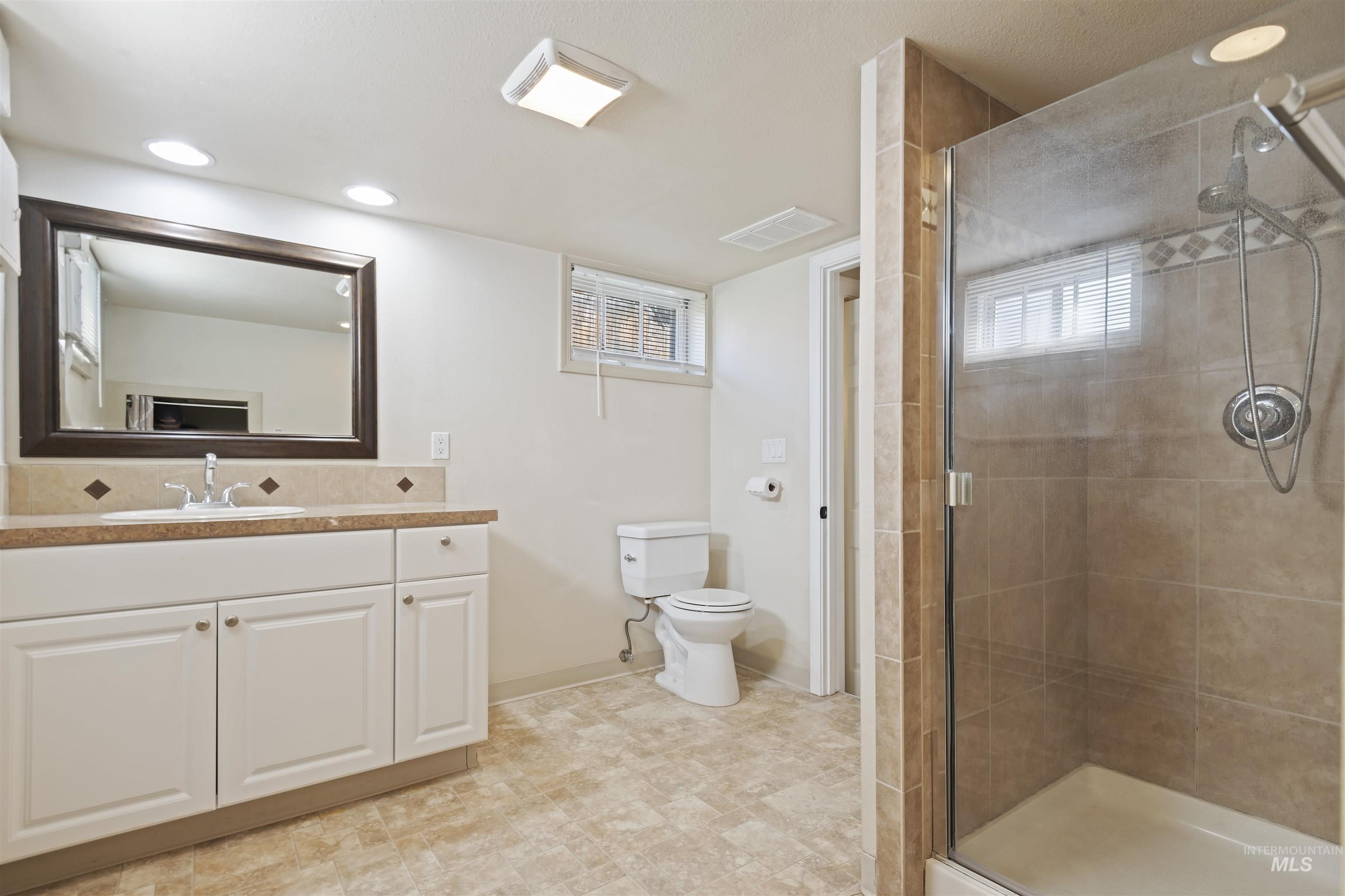 Bathroom with vanity, a shower stall, and recessed lighting