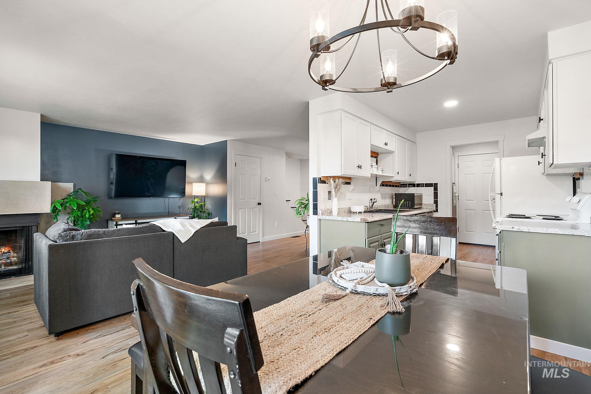 Dining space with light wood-style floors, a lit fireplace, a chandelier, and recessed lighting