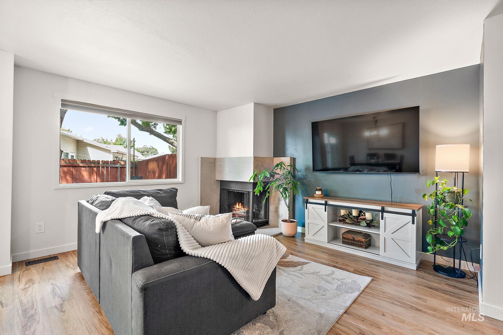 Living room with a multi sided fireplace and light wood finished floors