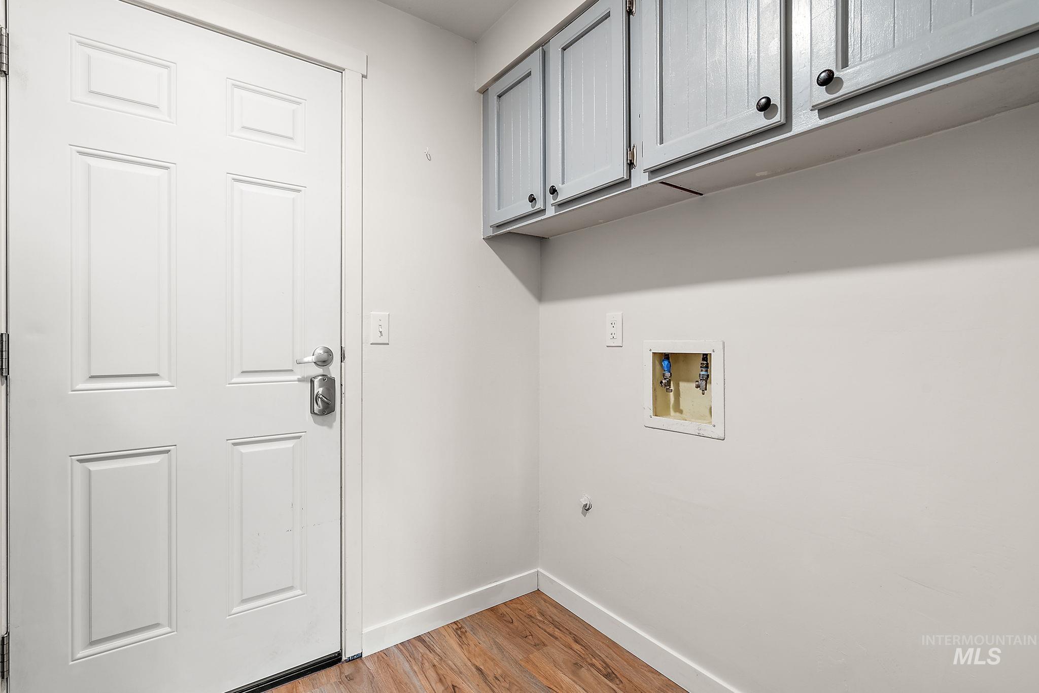 Laundry room featuring light wood-type flooring, cabinet space, and washer hookup
