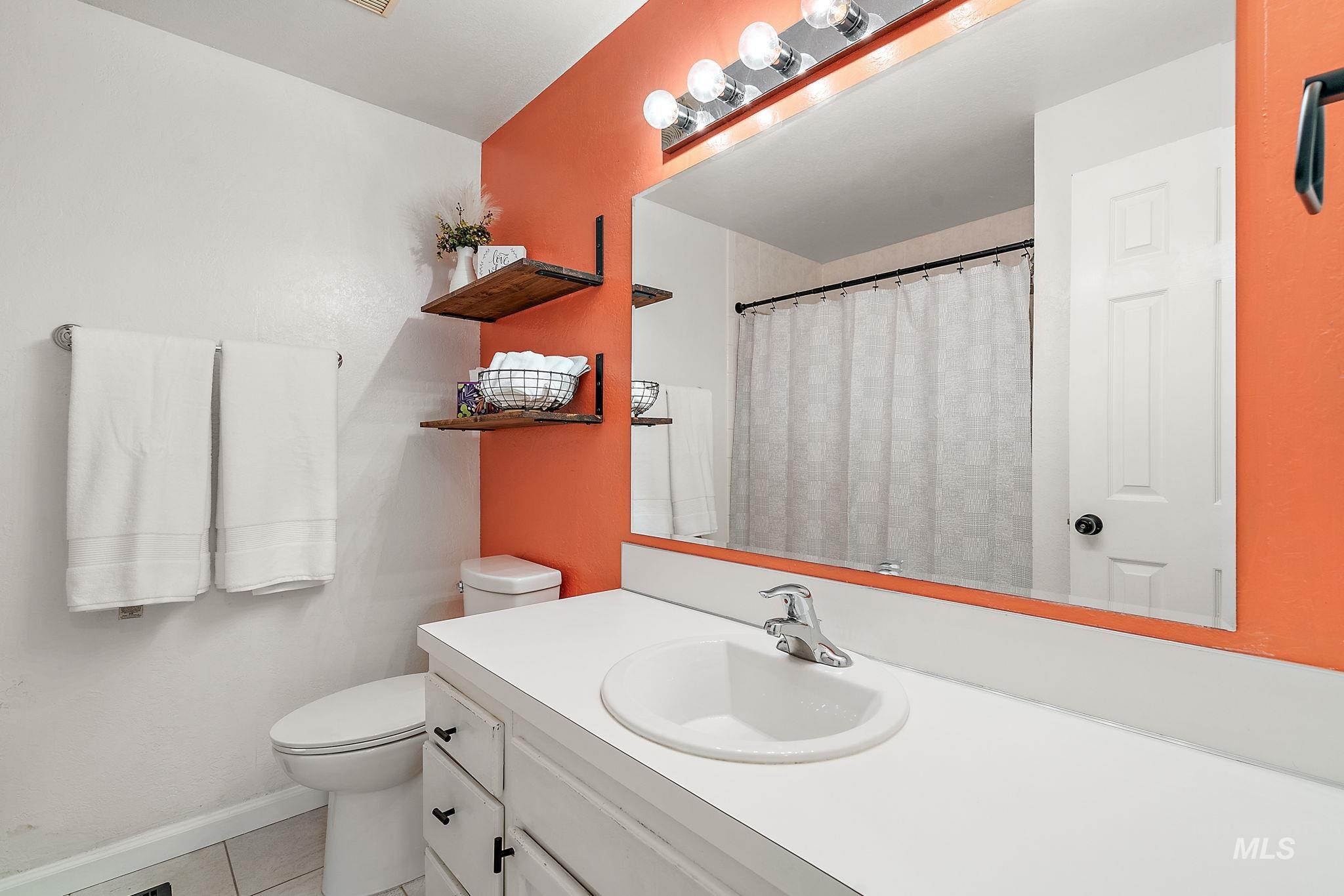 Upstairs bathroom with vanity, light tile patterned floors, and a shower with shower curtain