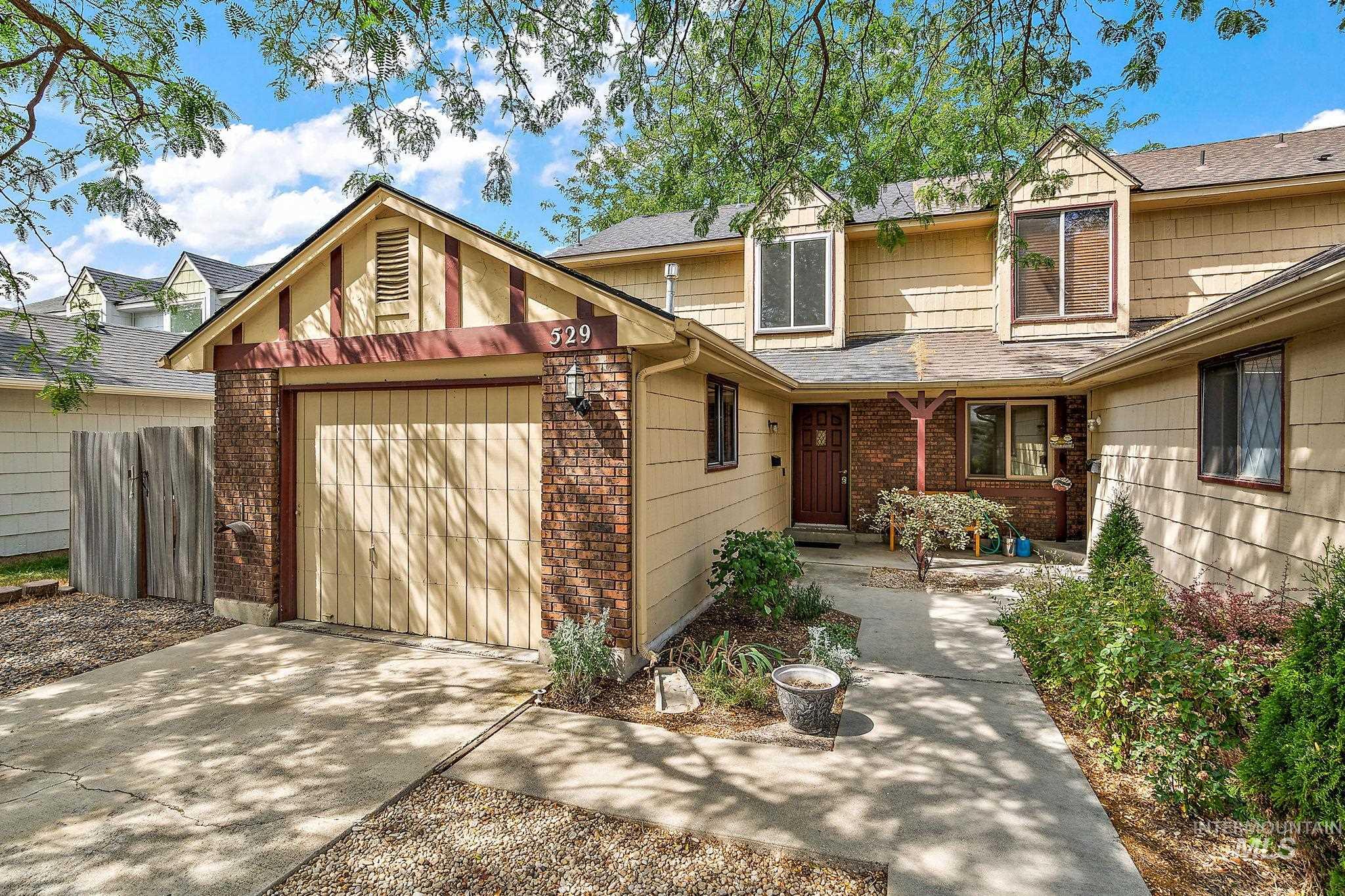 View of front of property featuring a garage, concrete driveway, brick siding, and roof with shingles