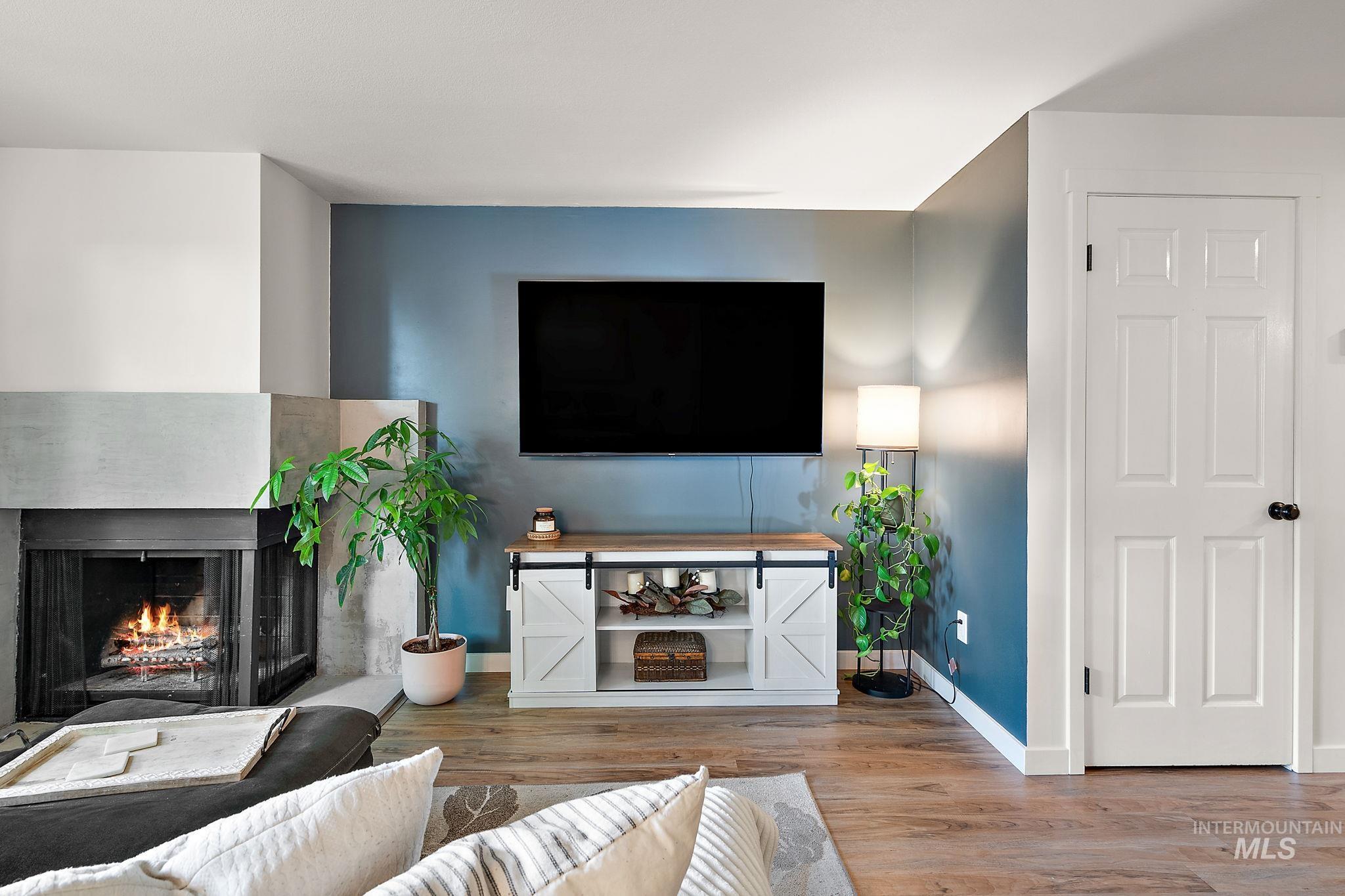 Living area with light wood-style floors and a multi sided fireplace