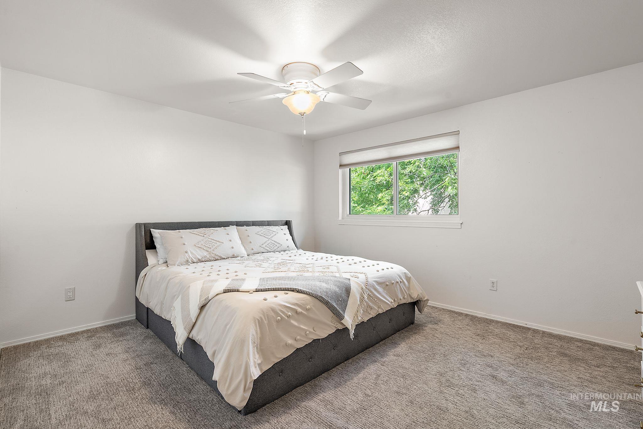 Carpeted bedroom featuring ceiling fan and baseboards