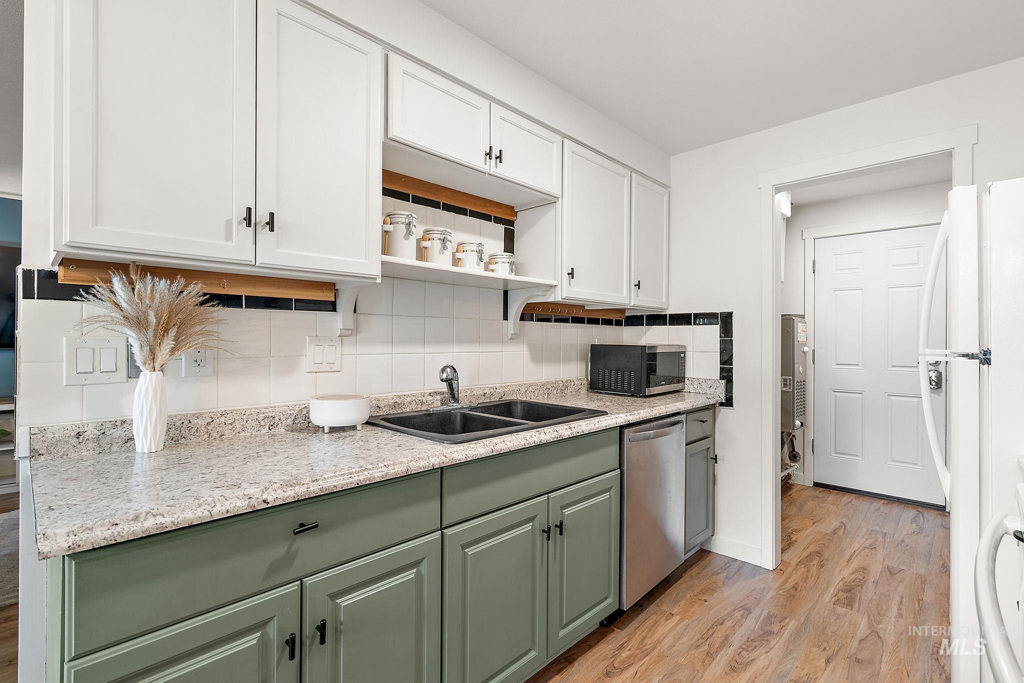 Kitchen featuring decorative backsplash, green cabinets, white cabinetry, light wood-type flooring, and open shelves