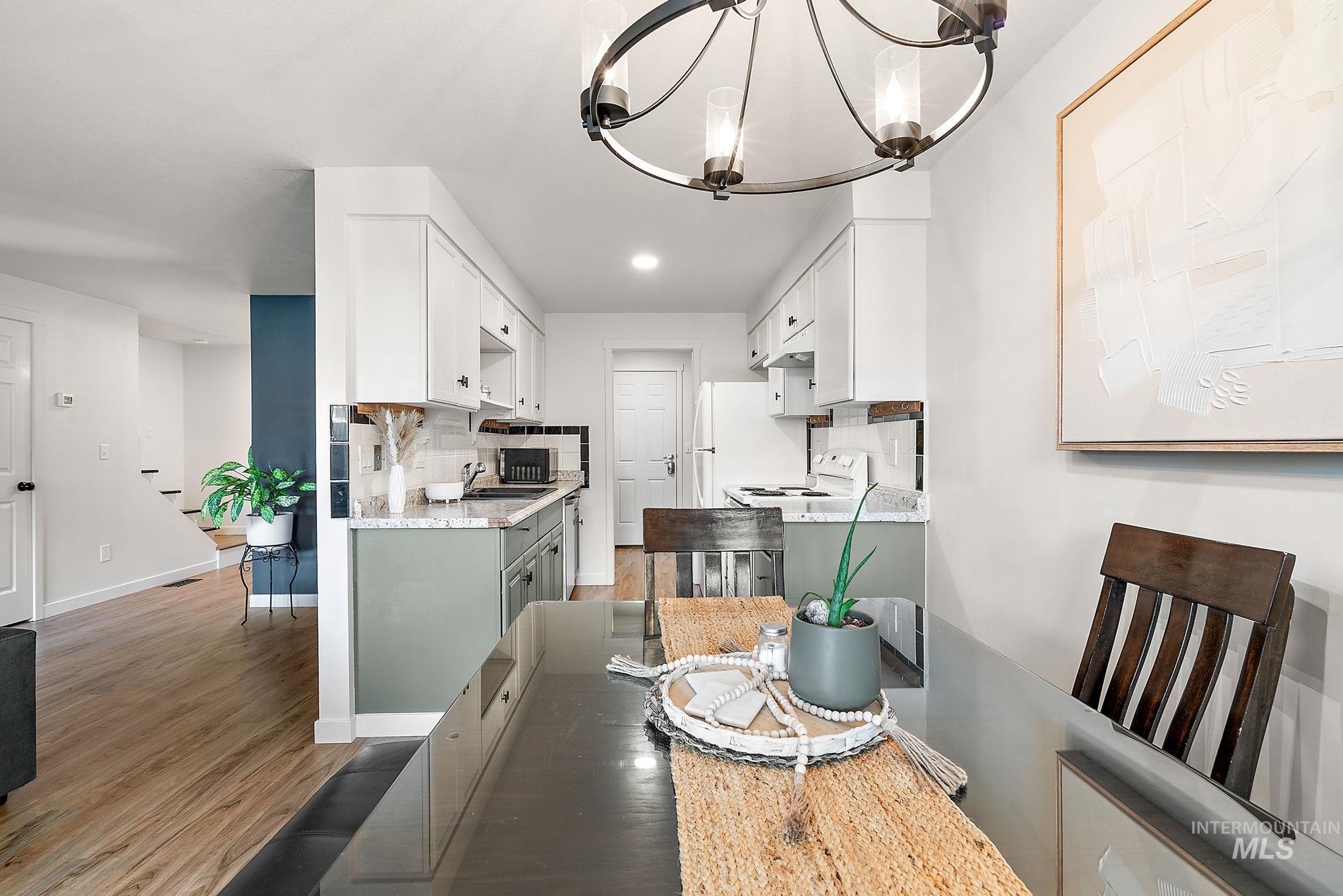 Dining area with light wood finished floors, a chandelier, and recessed lighting
