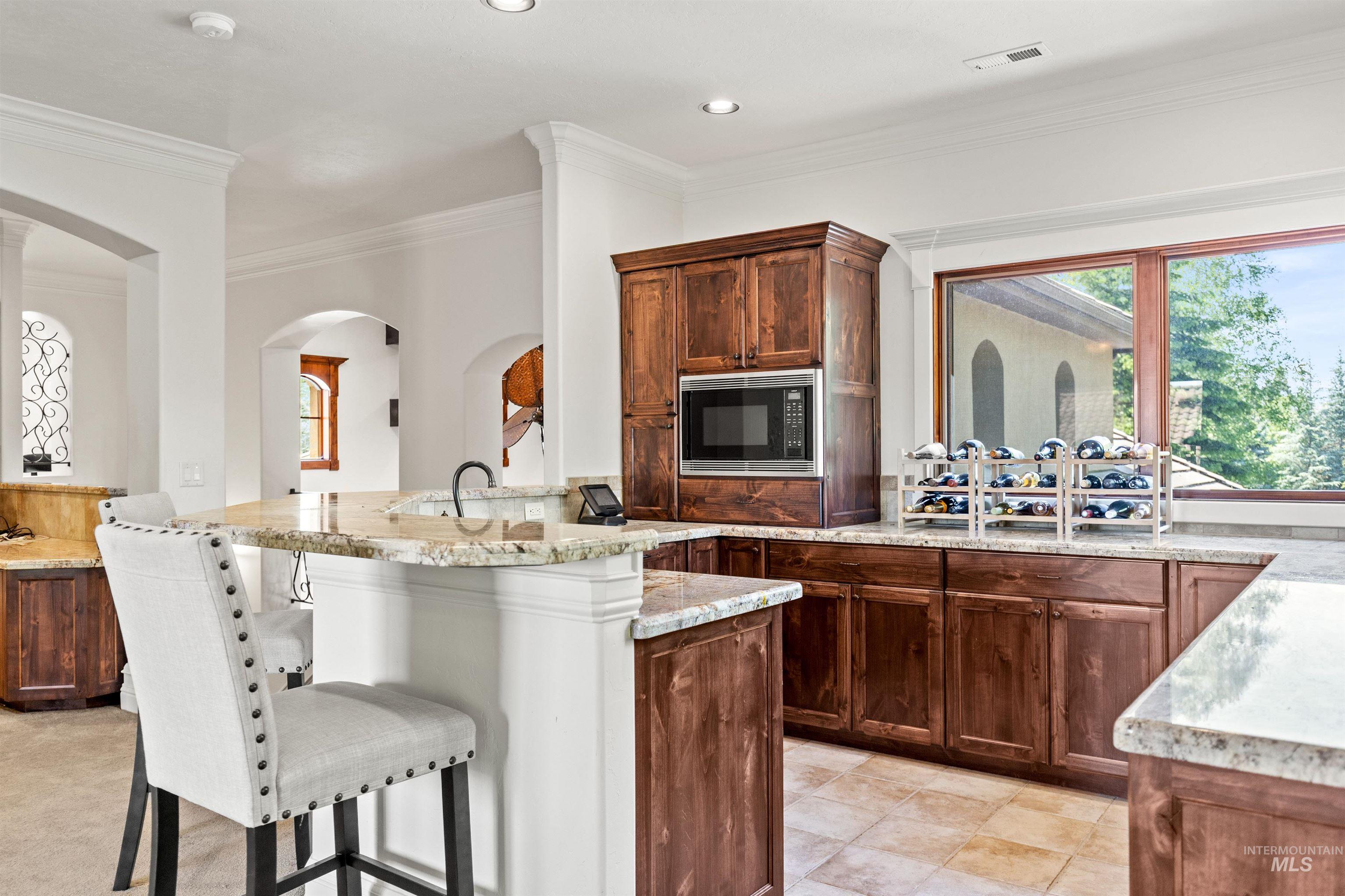 U-shaped kitchen island with granite countertops, integrated sink, and recessed lighting