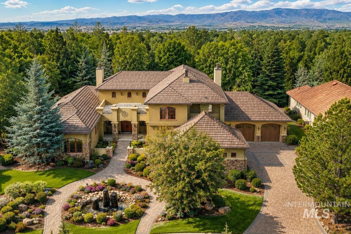 Stately residence featuring a tiled roof, stucco exterior, and a stone-clad foundation
