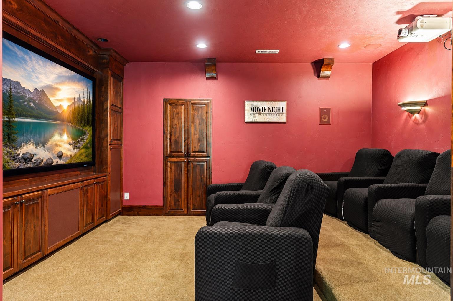 Dedicated media room featuring a large built-in entertainment center with a television, wood-finish cabinetry, and recessed lighting
