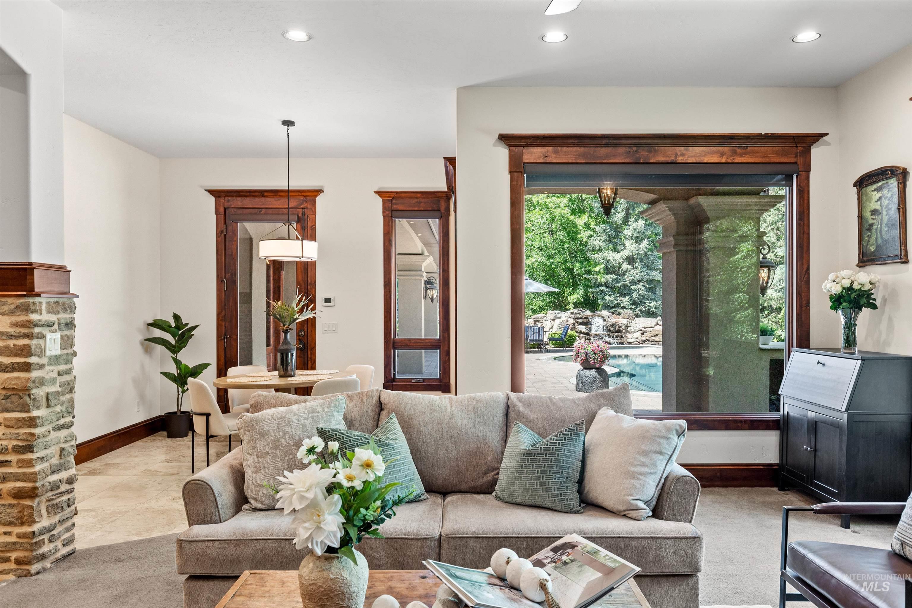 Open-concept living space featuring a large window with pool views, recessed lighting, and a stone accent wall