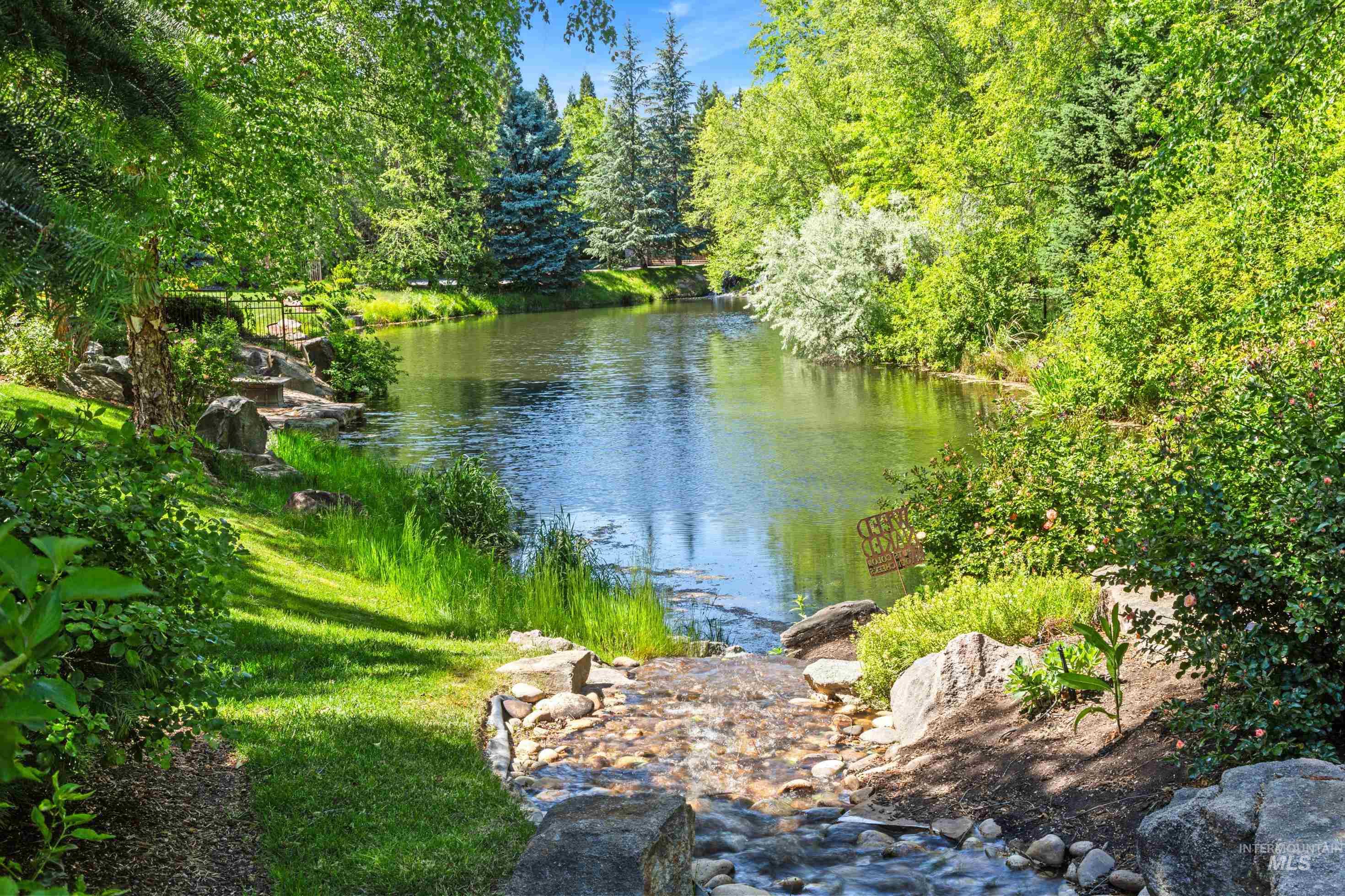 Natural water feature with a stone-lined stream flowing into a reflective pond