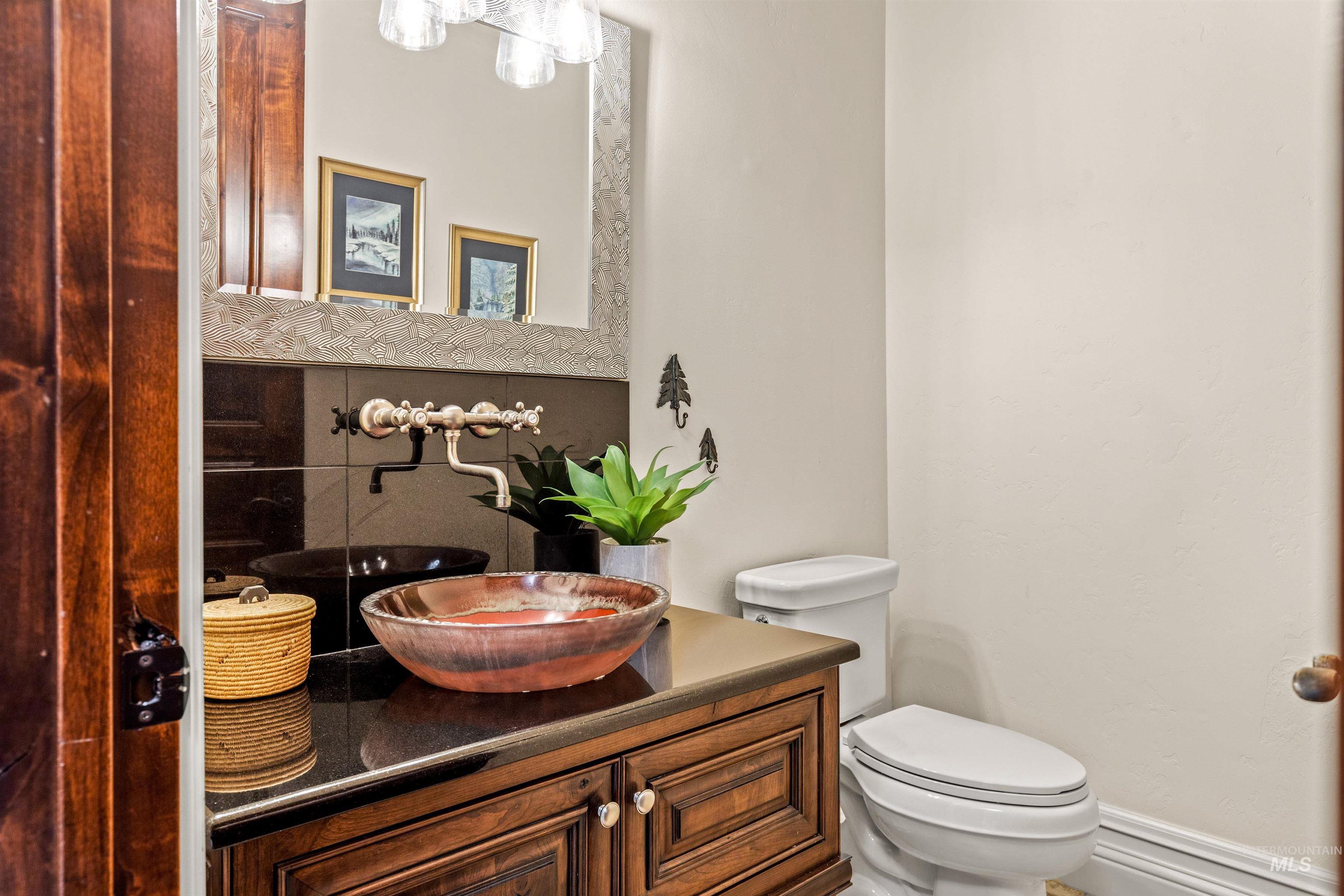 Powder room featuring a rich wood-finish vanity with a dark countertop and a decorative vessel sink