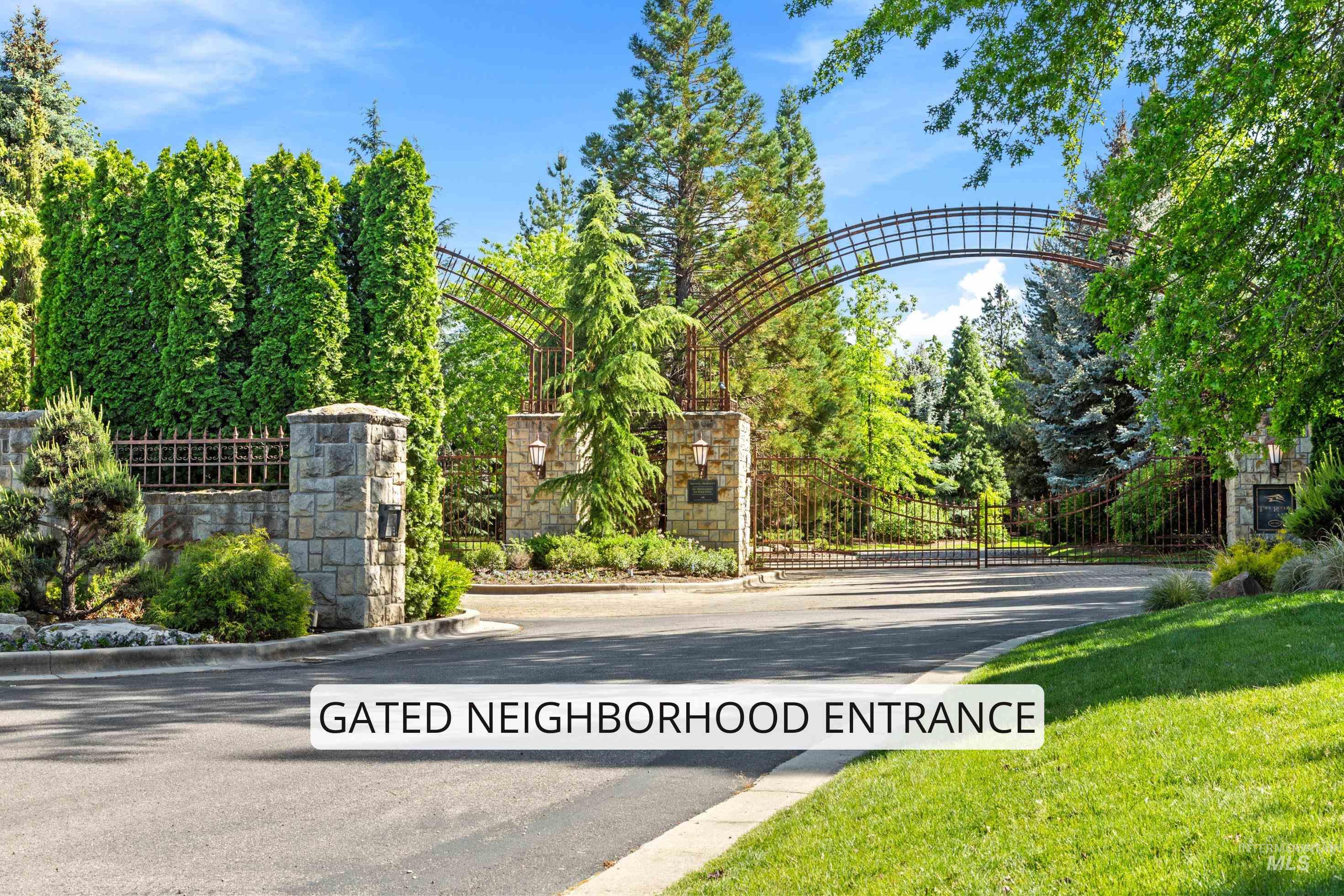 Gated entrance featuring stone pillars, decorative ironwork, and mature landscaping