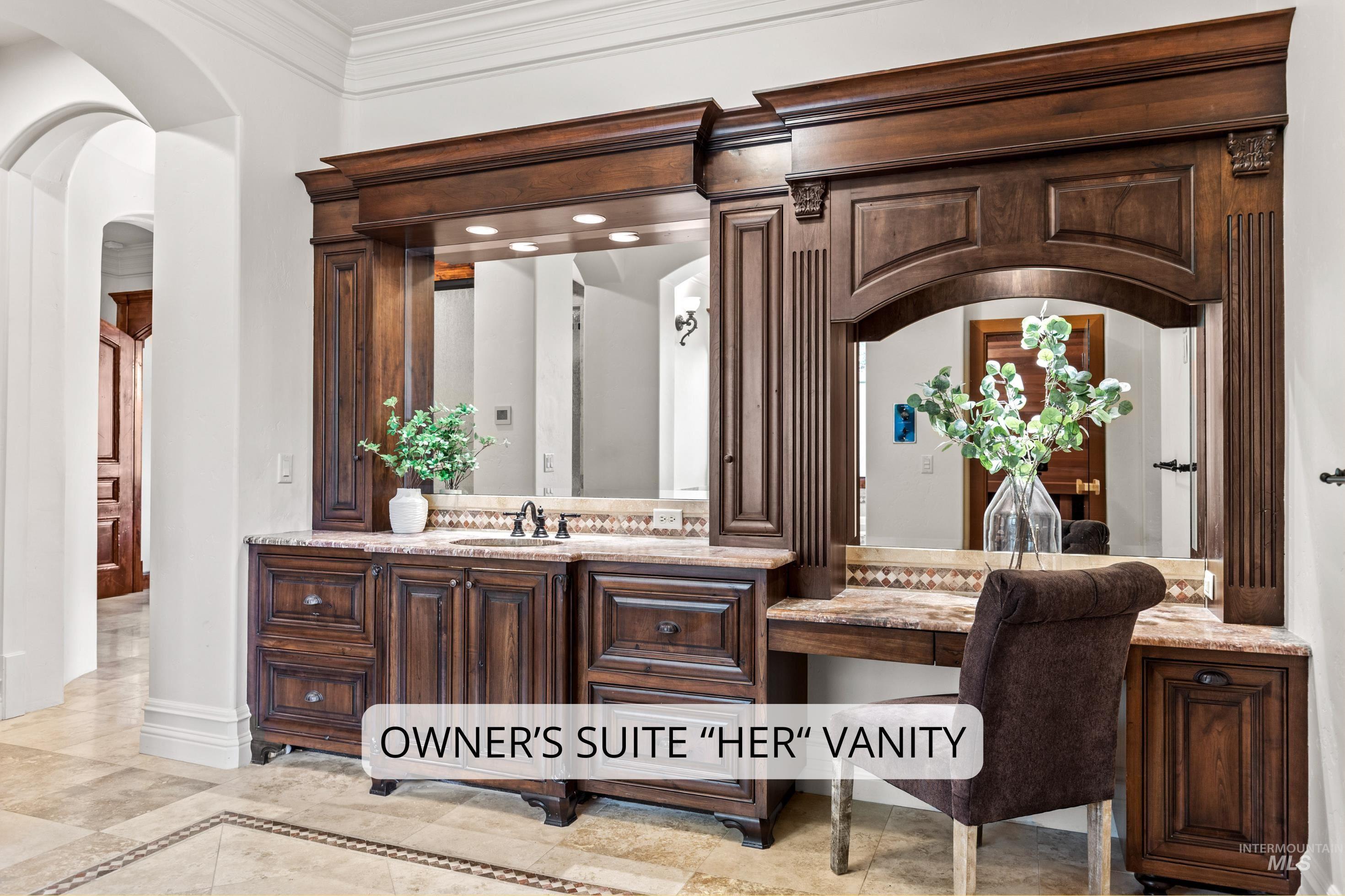 Custom built-in vanity with rich wood cabinetry, integrated mirrors, stone countertops, and decorative trim