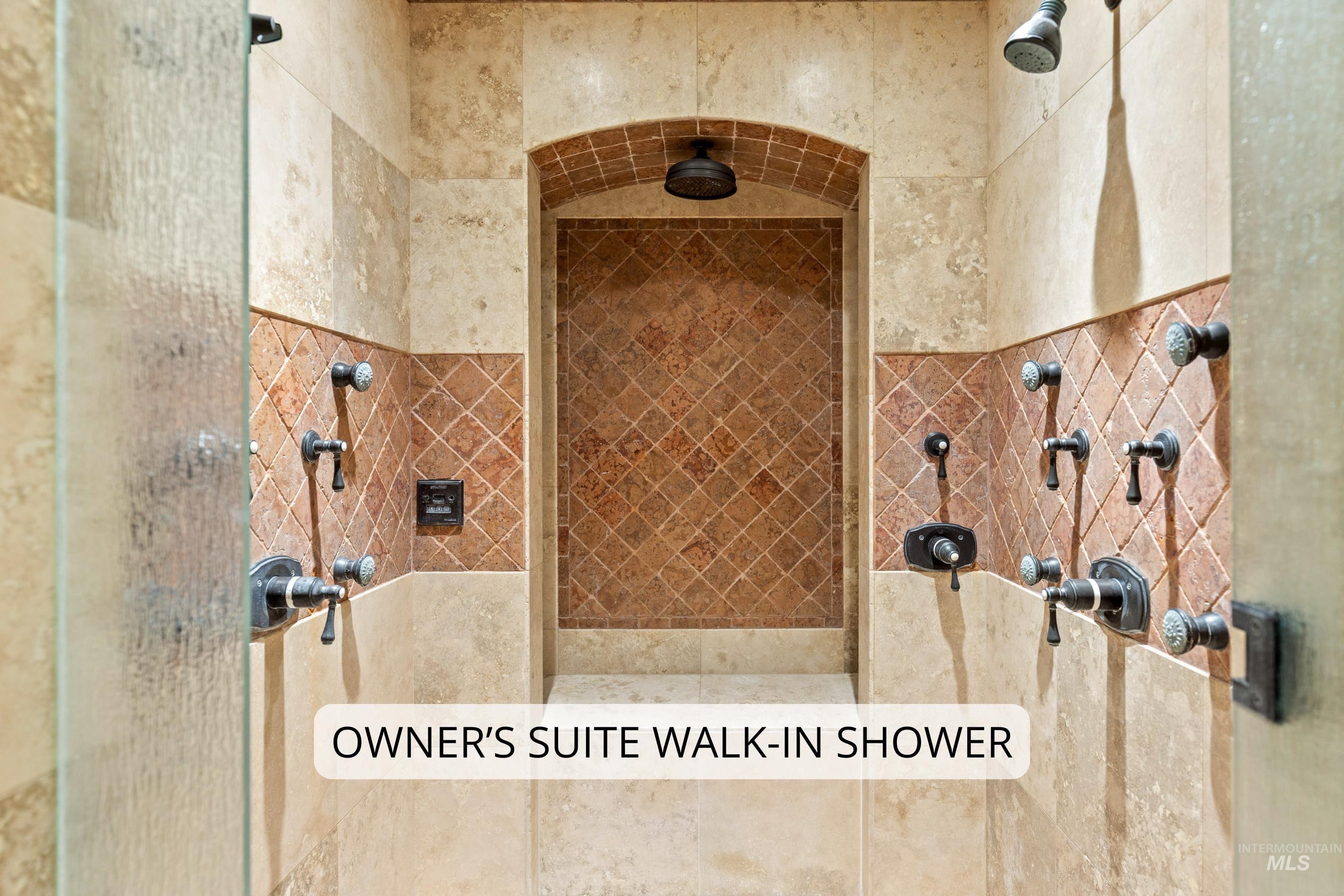 Tiled walk-in shower featuring multiple showerheads, individual temperature controls, and a recessed arch design