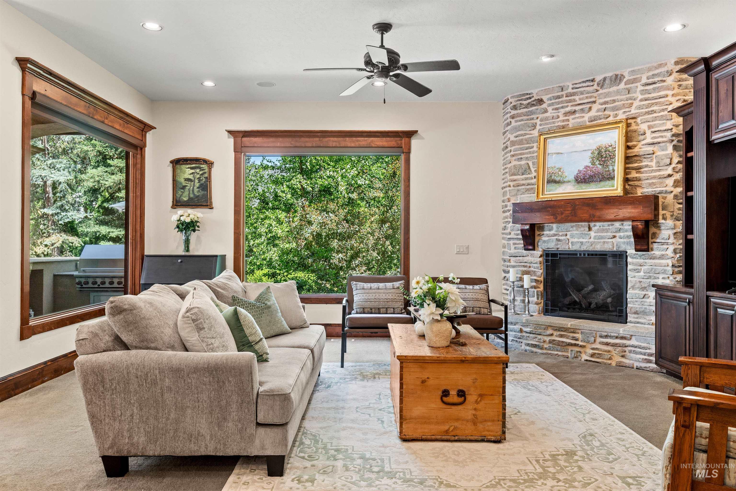 Living area featuring a stone-clad fireplace with a wood mantle, built-in cabinetry, and recessed lighting