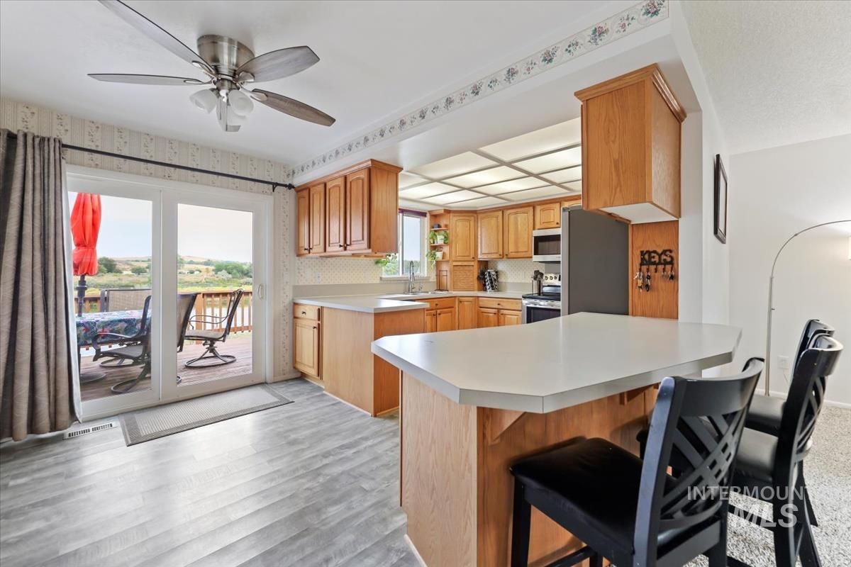 Kitchen featuring light countertops, a breakfast bar, a peninsula, stainless steel appliances, and a ceiling fan