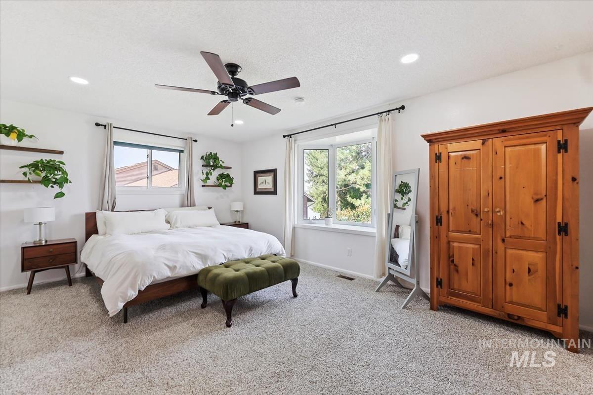 Bedroom featuring light carpet, multiple windows, a ceiling fan, a textured ceiling, and recessed lighting