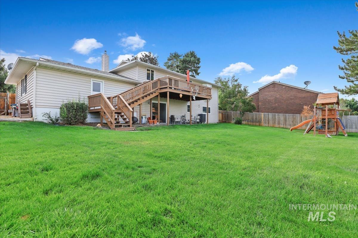 Back of property featuring stairway, a playground, a fenced backyard, a chimney, and a deck