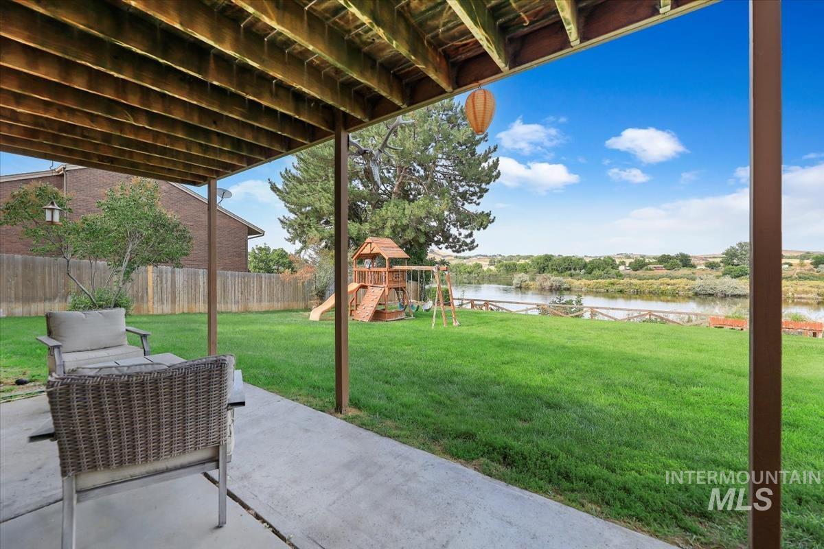 Fenced backyard featuring a water view, a playground, and a patio