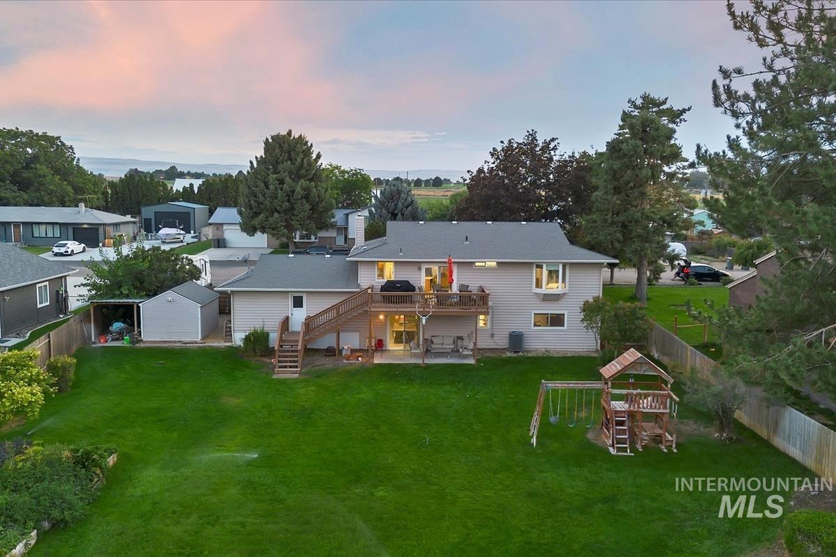 Back of house with a playground, stairs, a patio, a wooden deck, and a fenced backyard