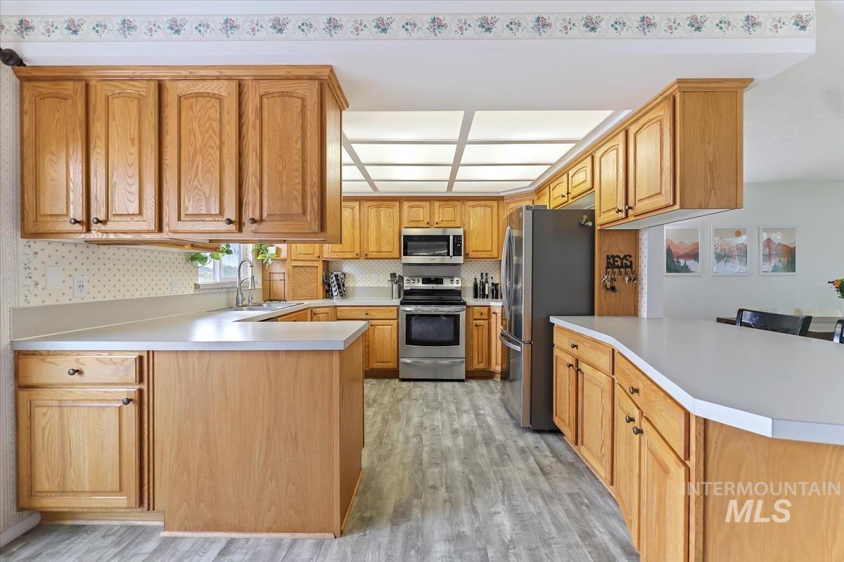 Kitchen with a peninsula, light countertops, stainless steel appliances, and light wood-style flooring