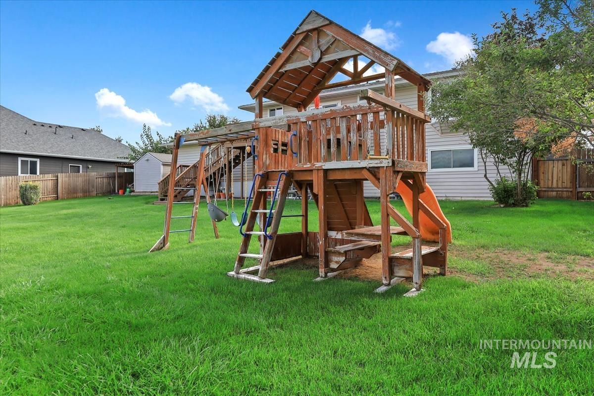 View of play area with a fenced backyard, a wooden deck, and a storage unit