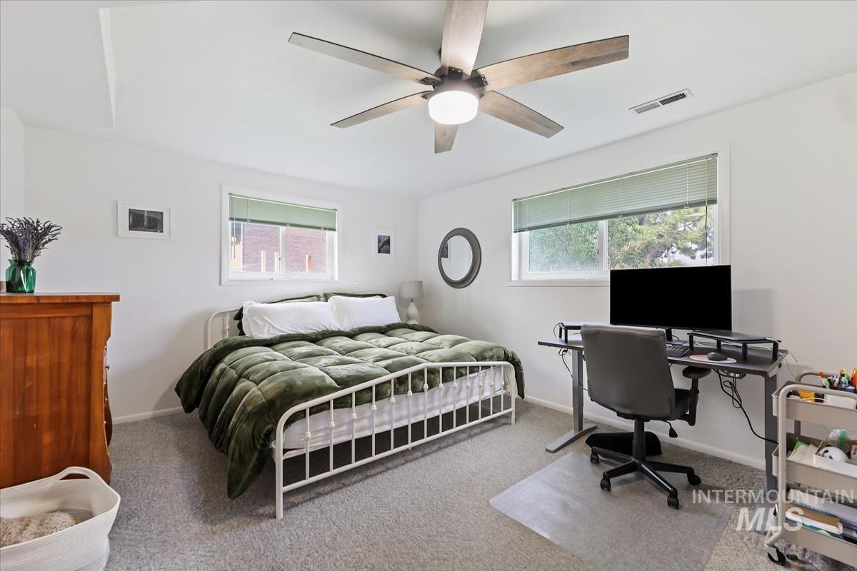 Bedroom with multiple windows, light colored carpet, and a ceiling fan