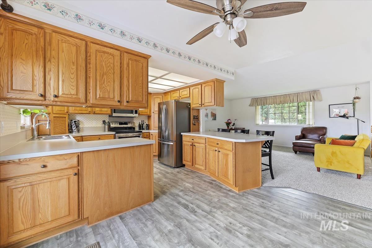 Kitchen featuring a peninsula, open floor plan, light countertops, and appliances with stainless steel finishes