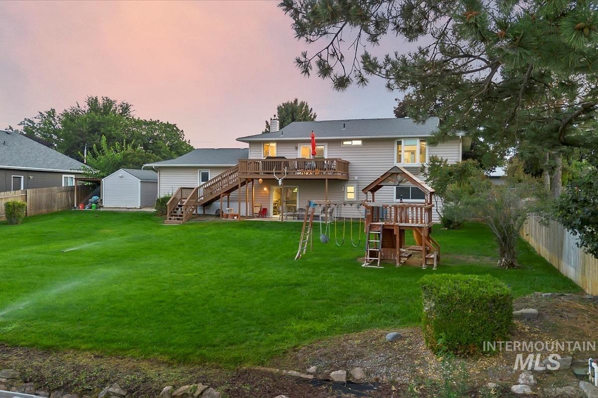 Back of property with stairs, a wooden deck, a chimney, a fenced backyard, and a playground