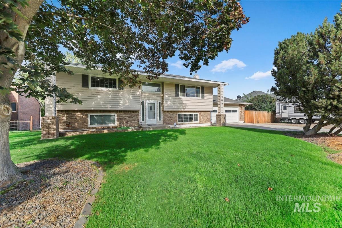 Raised ranch featuring brick siding, a garage, and driveway