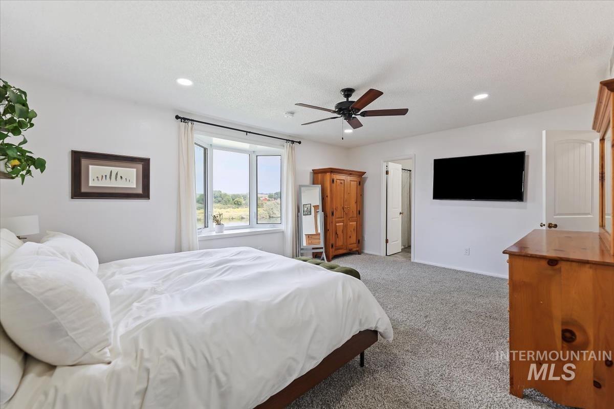 Carpeted bedroom with a ceiling fan, recessed lighting, and a textured ceiling