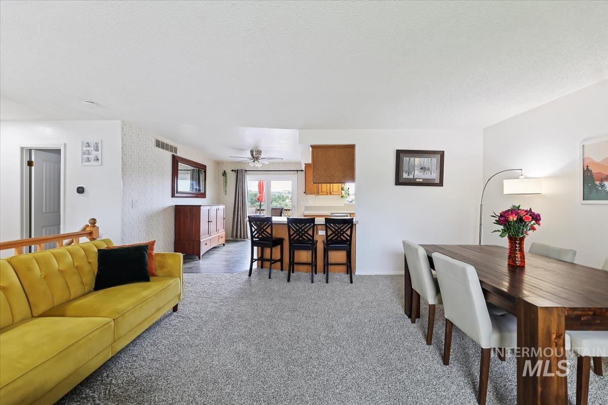 Dining room with light carpet, a textured ceiling, and ceiling fan