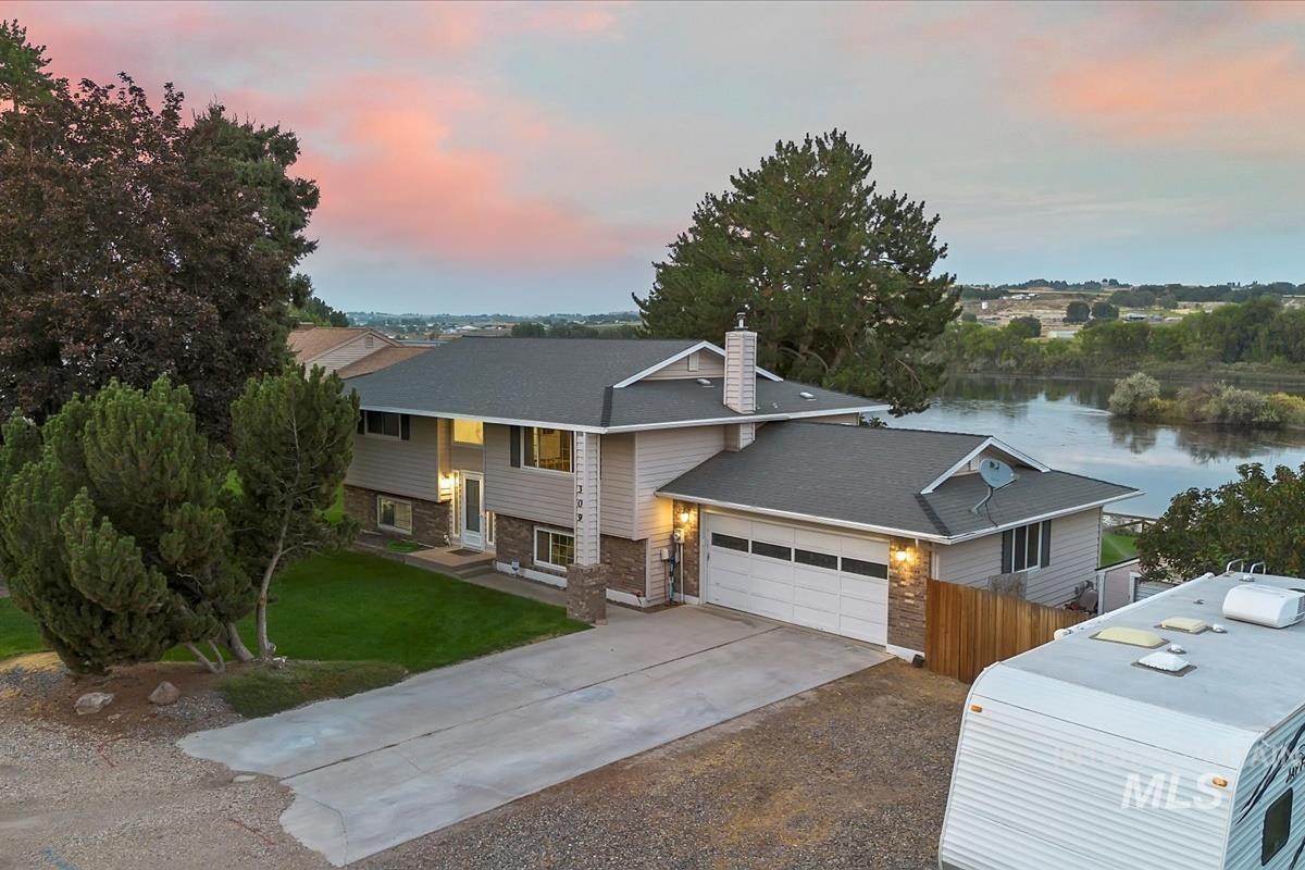 Raised ranch featuring concrete driveway, a chimney, a water view, and brick siding