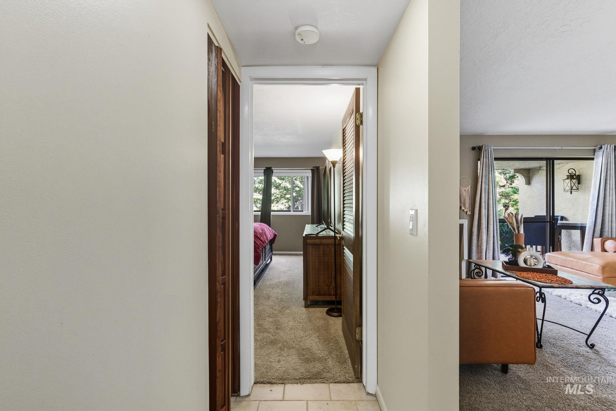 Hallway with light carpet and light tile patterned flooring