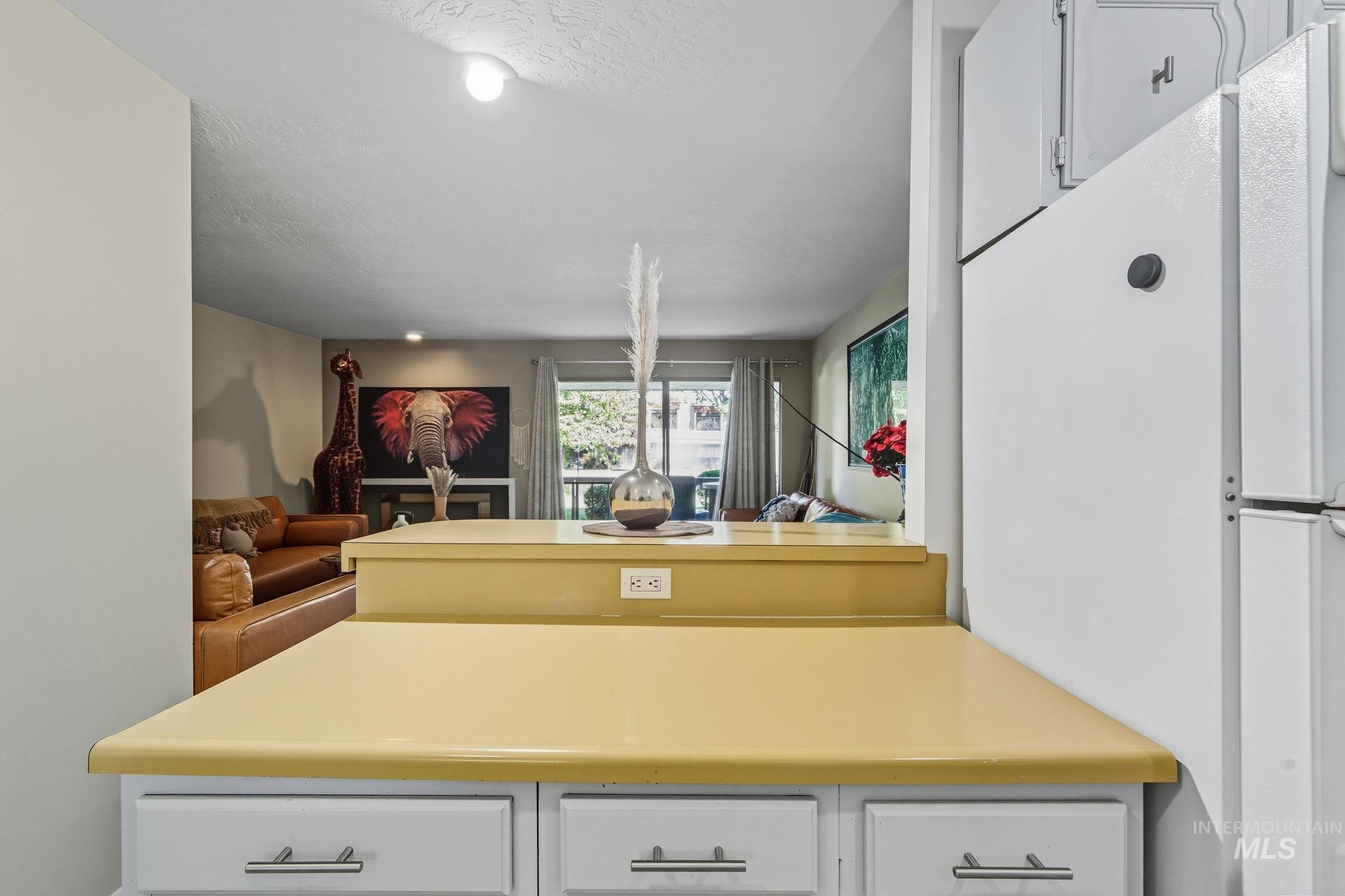 Kitchen with white cabinets, open floor plan, a peninsula, freestanding refrigerator, and light countertops