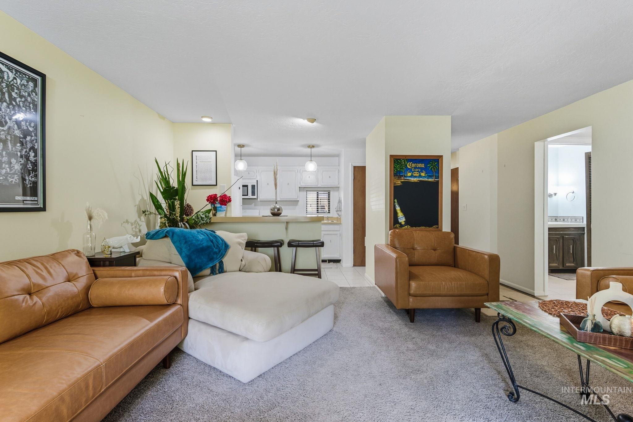 Living area with light colored carpet and light tile patterned floors