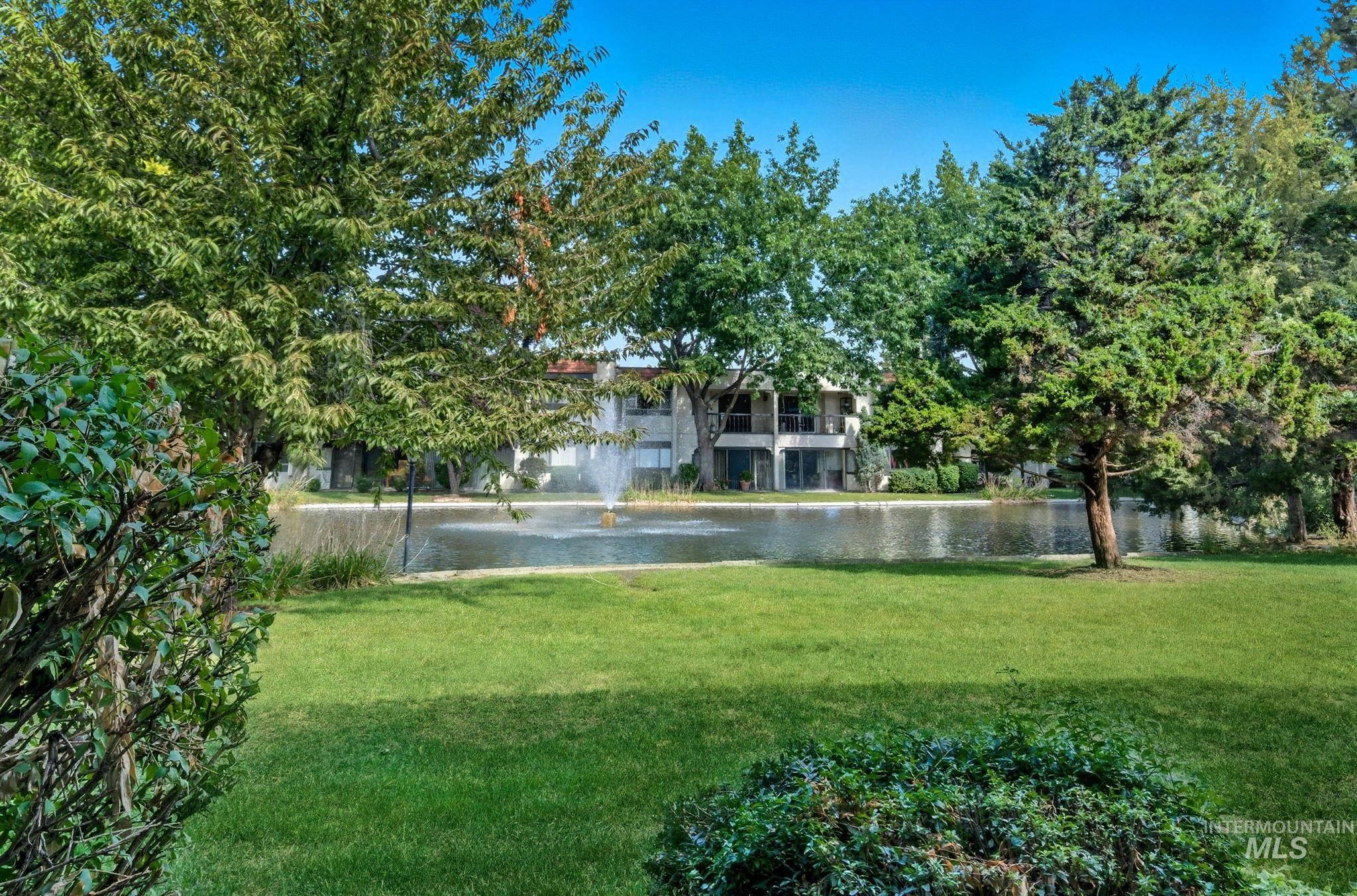 View of green lawn with a water view and a balcony