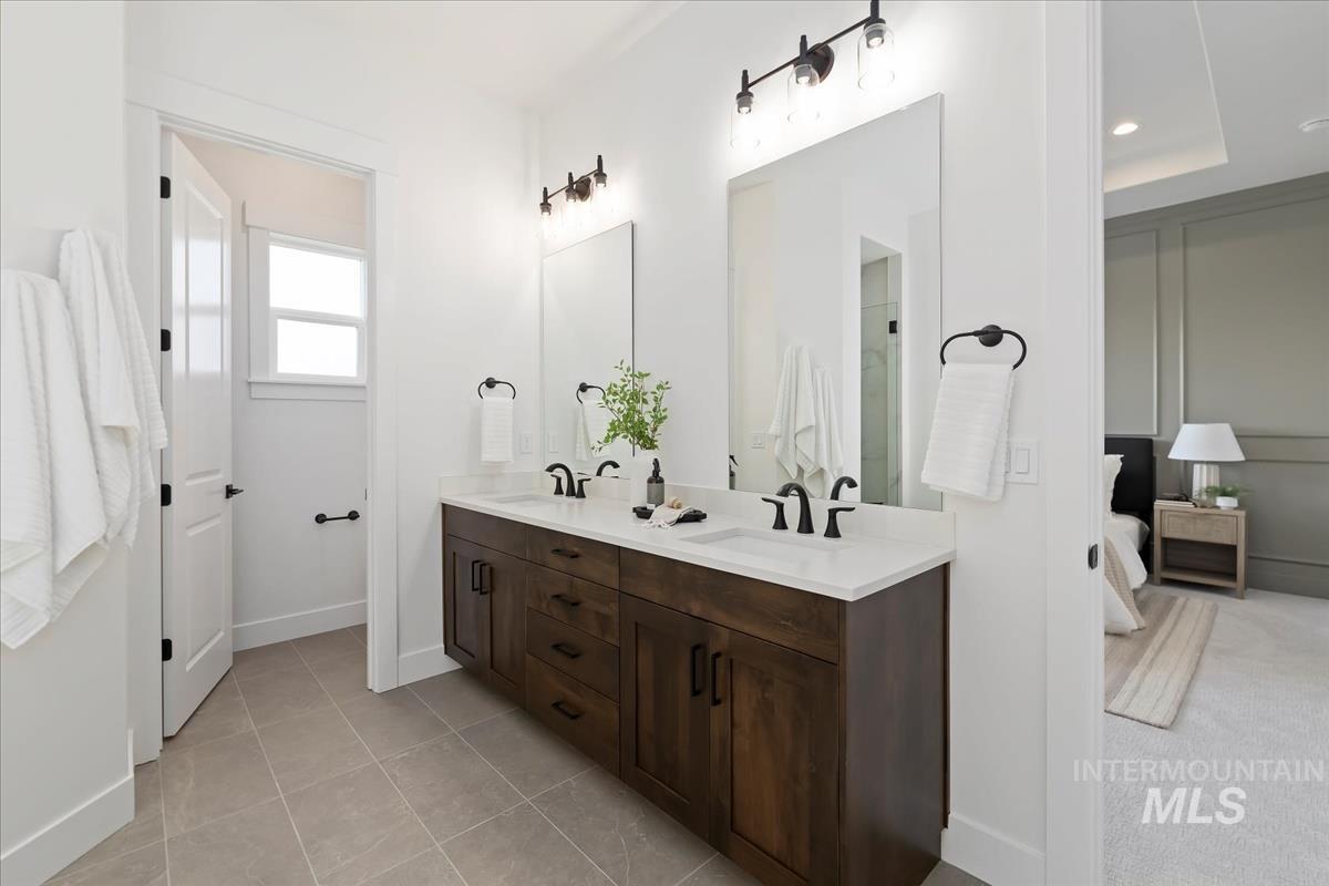 Ensuite bathroom with double vanity and light tile patterned floors