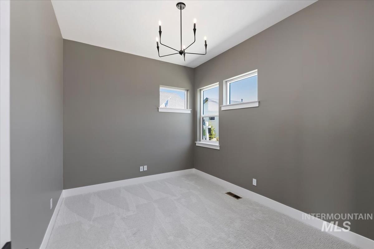Spare room with light colored carpet and a chandelier
