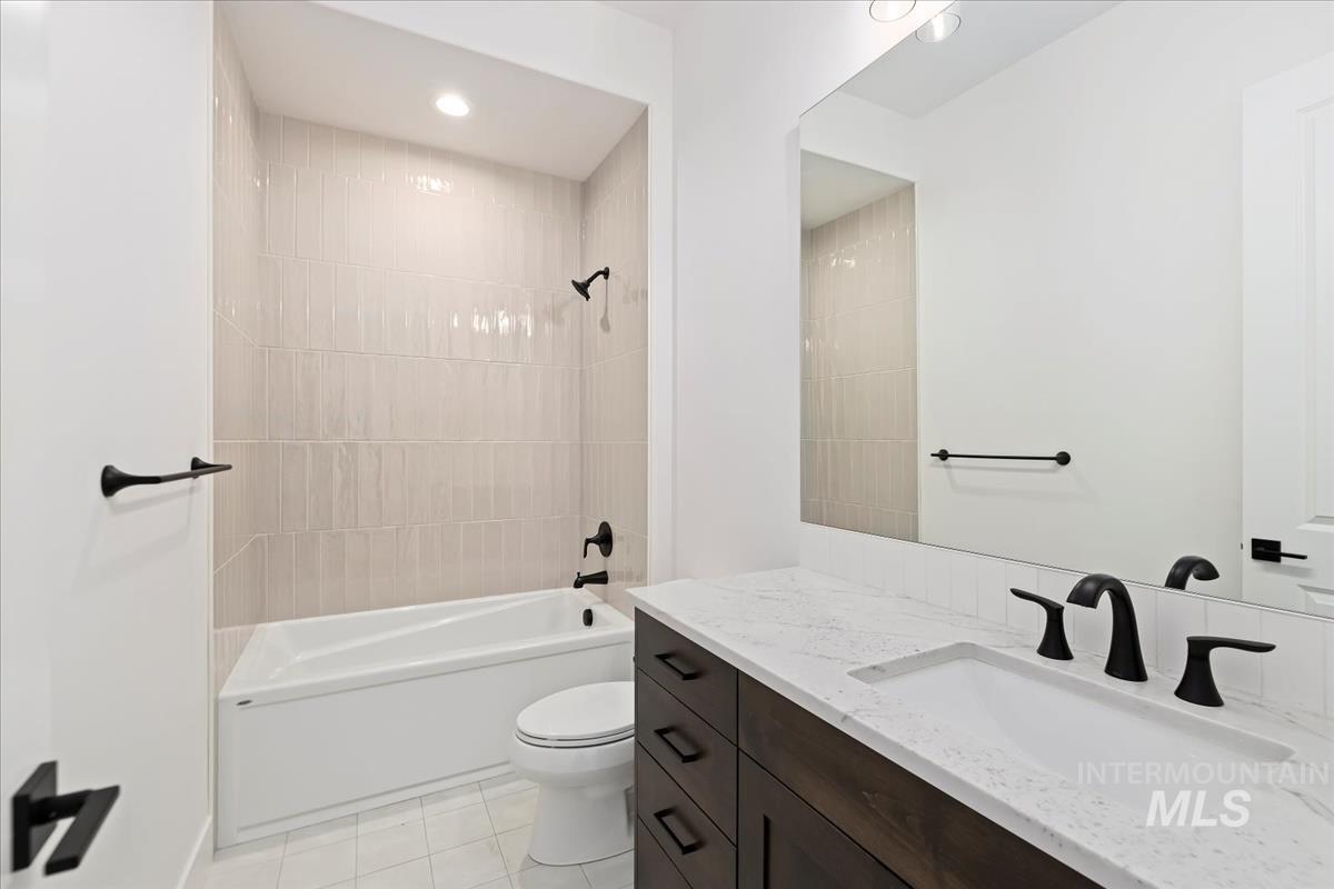 Full bath with bathtub / shower combination, vanity, and light tile patterned floors