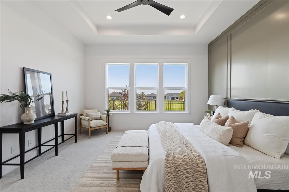 Bedroom with carpet, a ceiling fan, a tray ceiling, and recessed lighting