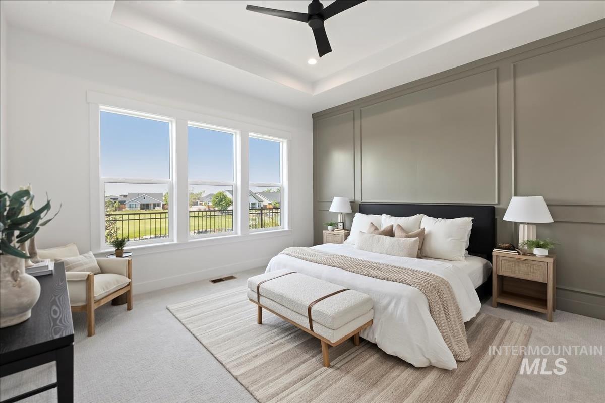 Bedroom featuring a decorative wall, a raised ceiling, carpet flooring, a ceiling fan, and recessed lighting