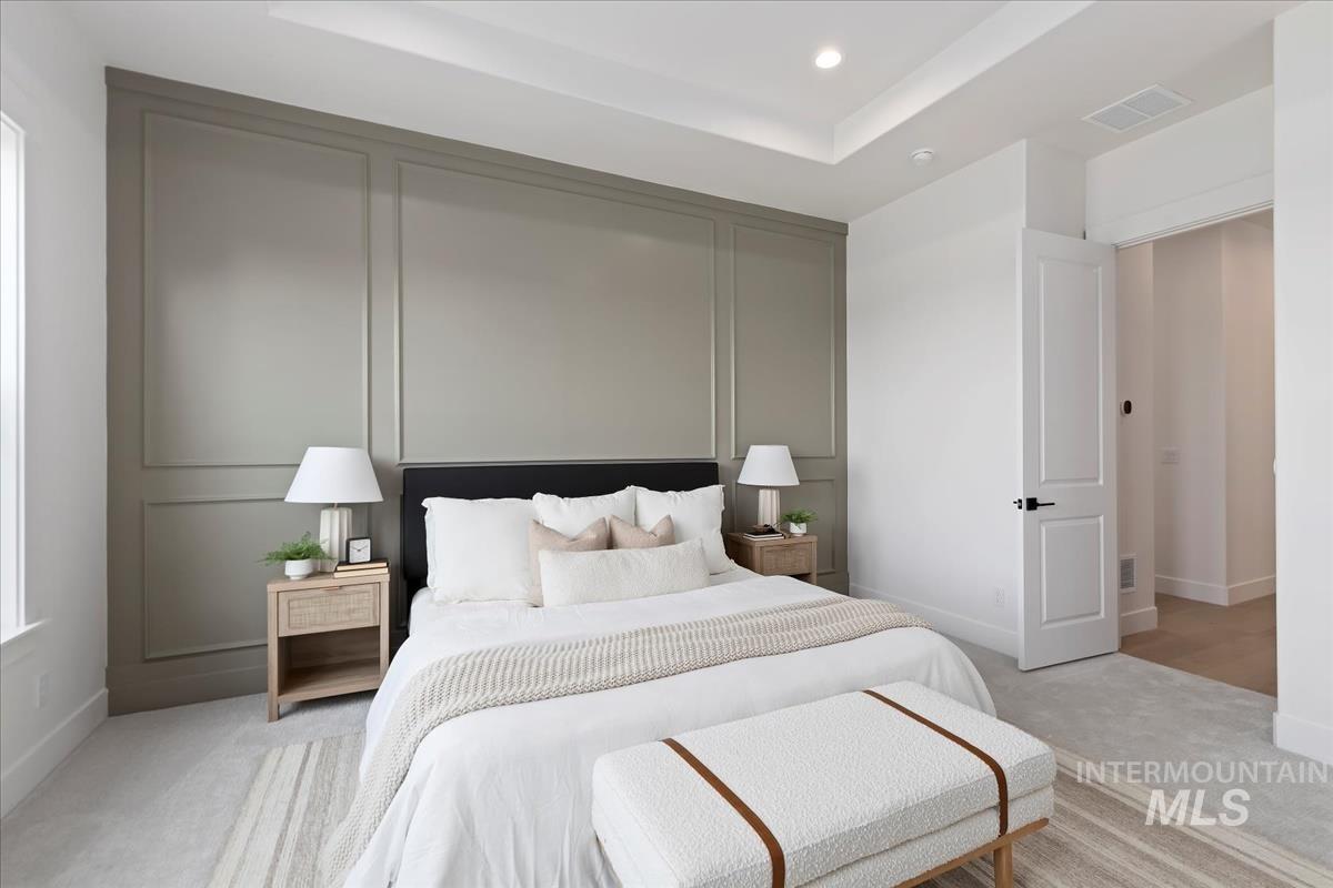 Bedroom with carpet floors, a raised ceiling, and recessed lighting