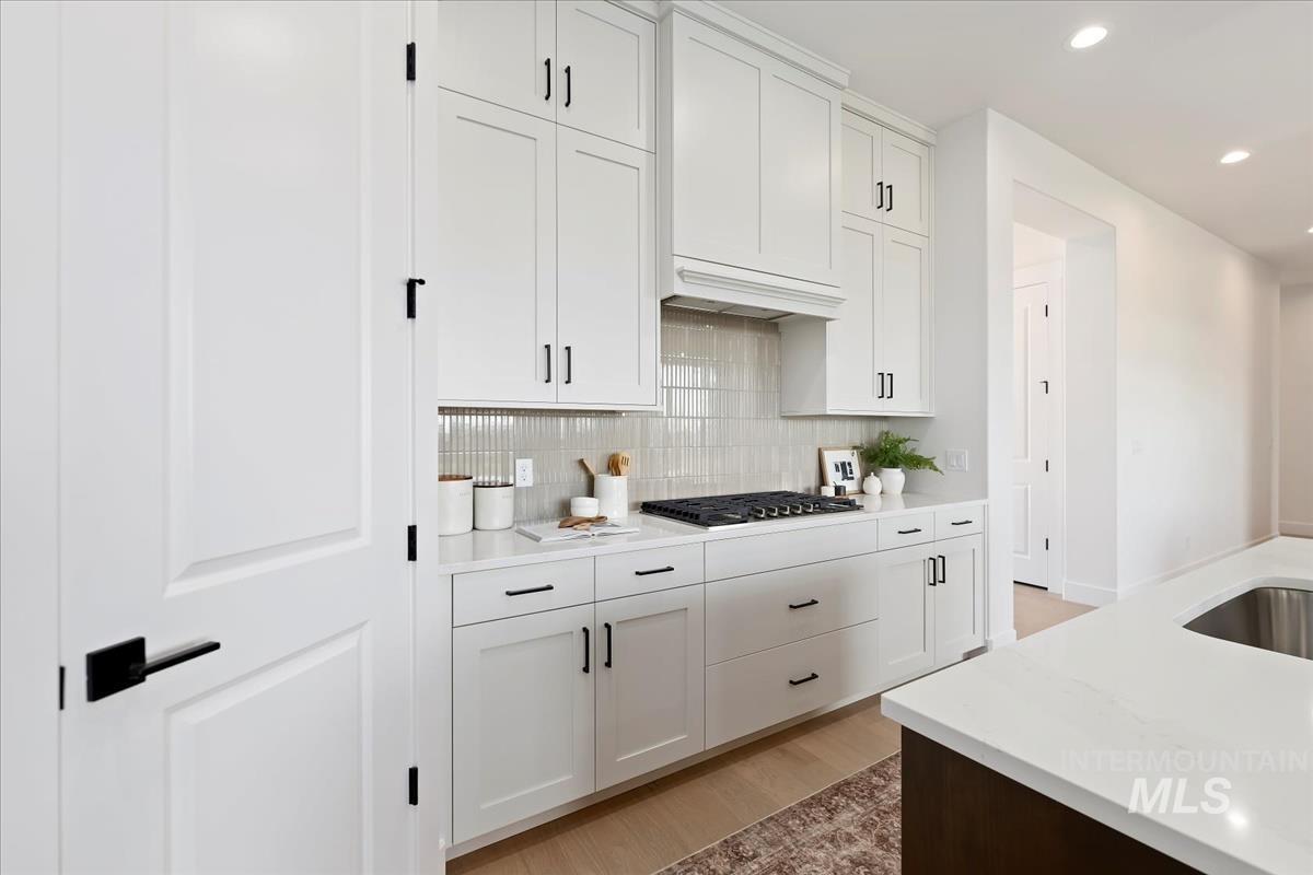 Kitchen featuring white cabinetry, tasteful backsplash, light wood finished floors, and recessed lighting