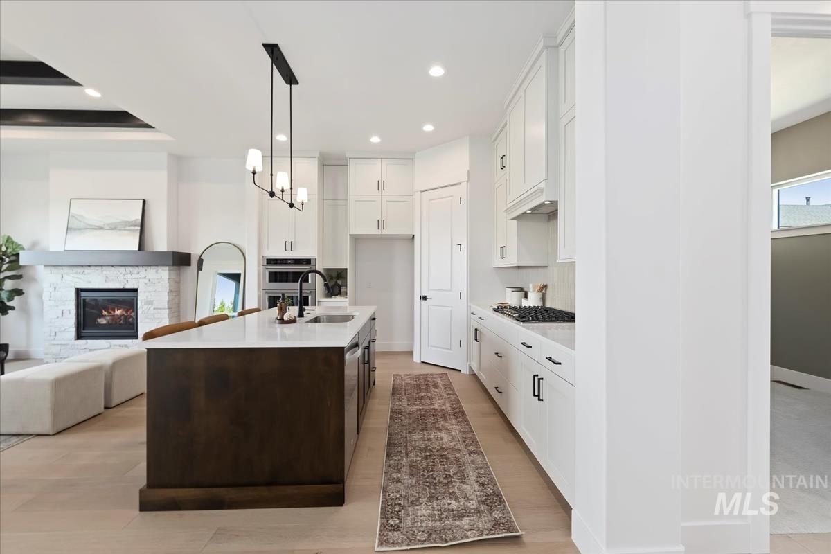 Kitchen featuring a center island with sink, white cabinetry, dark brown cabinets, recessed lighting, and open floor plan