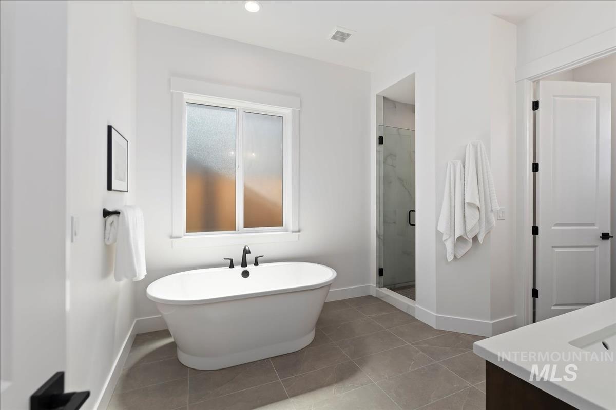 Full bathroom with a marble finish shower, a freestanding bath, vanity, and light tile patterned floors