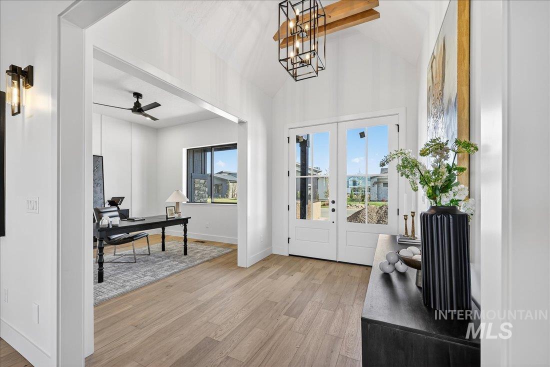 Entrance foyer with light wood-style floors, french doors, vaulted ceiling, a ceiling fan, and a chandelier