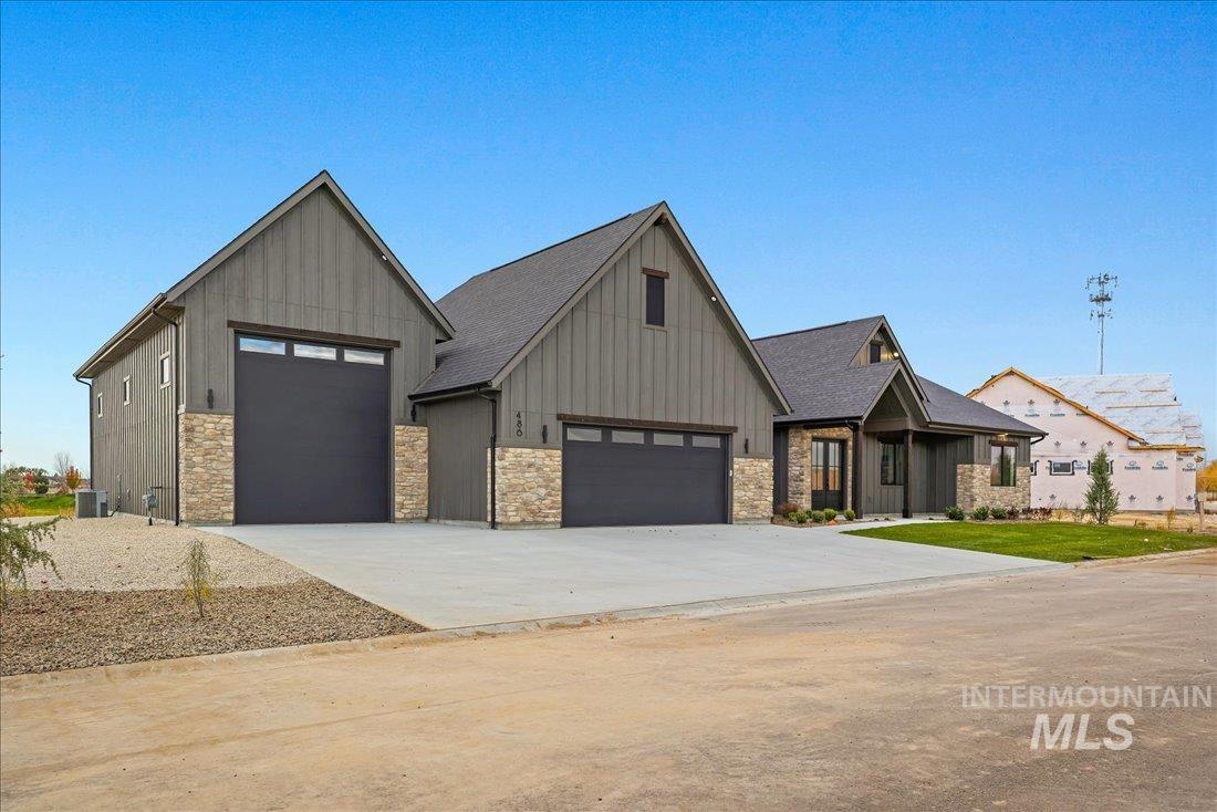 View of front of property featuring stone siding, board and batten siding, concrete driveway, and a garage