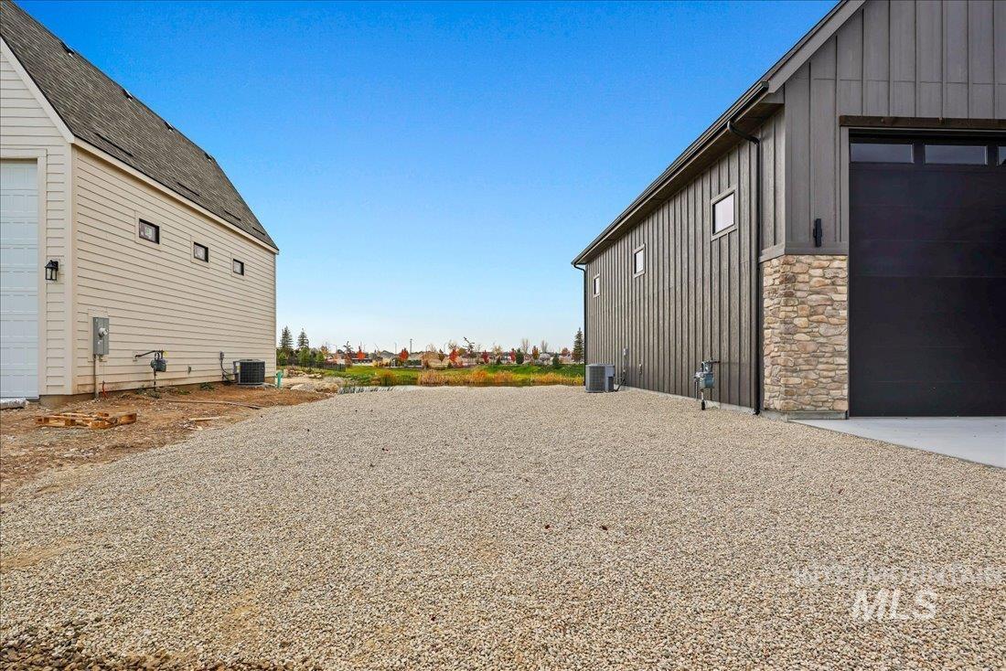 View of side of home featuring board and batten siding, a garage, stone siding, and an outdoor structure